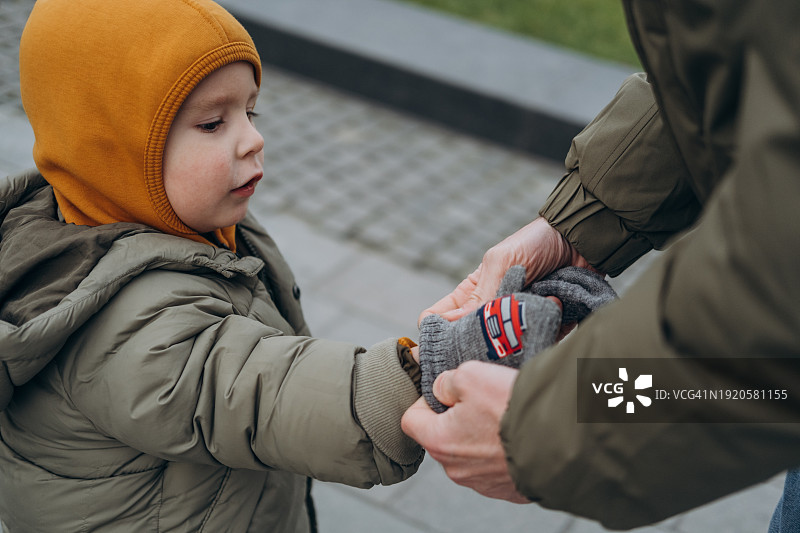 寒冷的天气里父亲为儿子戴上手套图片素材