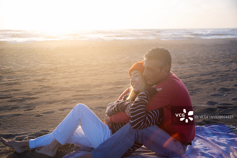 情侣在阳光明媚的冬日海滩上放松图片素材