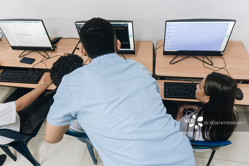 老师在学校的电脑室里辅导学生图片素材