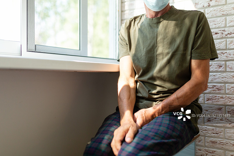 戴呼吸面罩独自坐在阳台上的年长男人图片素材