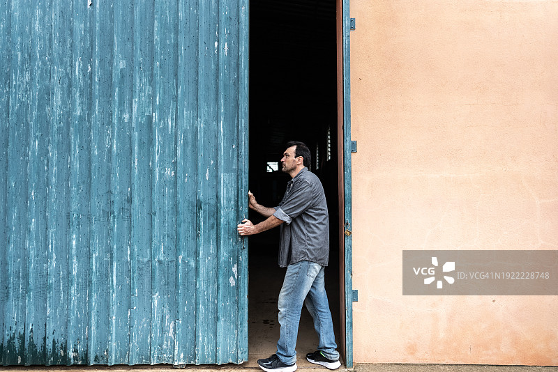 成熟的农民男人打开乡村场景中的仓库门图片素材