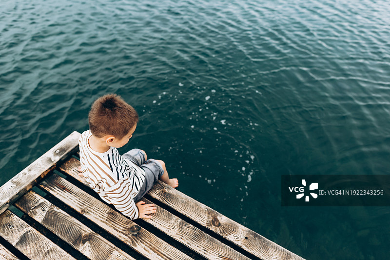 穿着条纹T恤看着大海的沉思男孩图片素材