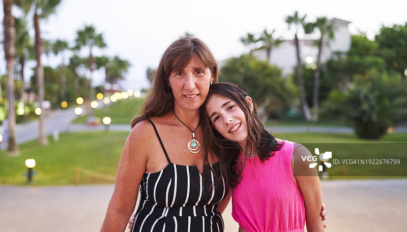 在花园小路上拥抱女儿的女人肖像图片素材