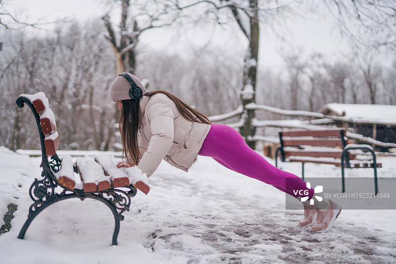 年轻女人在冬天长椅上做俯卧撑图片素材