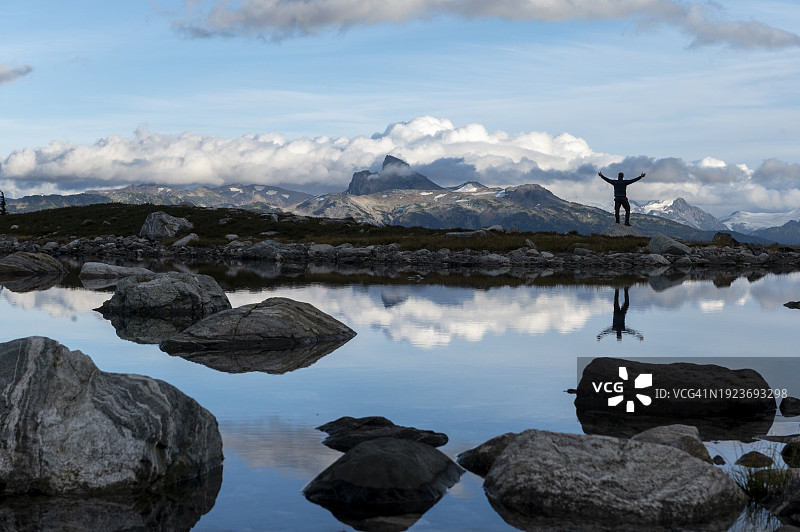 背包客在阿尔卑斯湖附近高兴地跳跃图片素材