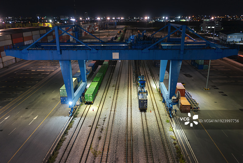 起重机在夜间从货运列车上装卸集装箱，用于商业物流、进出口运输或货运的鸟瞰图图片素材