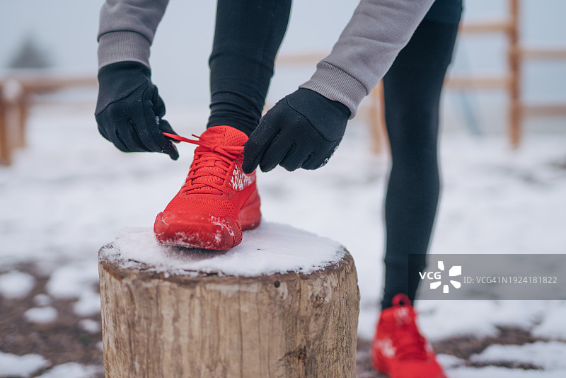 冬季户外训练中，系跑鞋并在伸展运动中休息的年轻男人图片素材