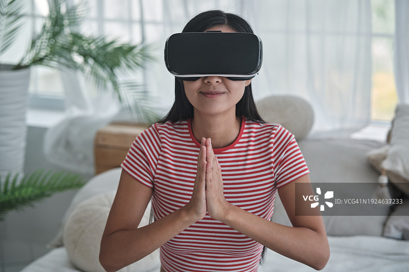 虚拟现实冥想缓解焦虑：亚洲女性在家中冥想图片素材