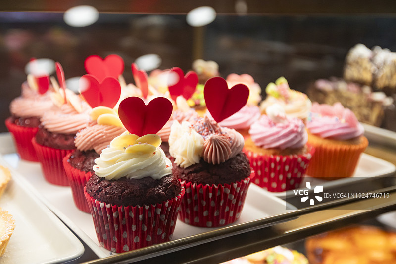 情人节红色天鹅绒纸杯蛋糕，白色糖霜和鲜红色心形装饰图片素材