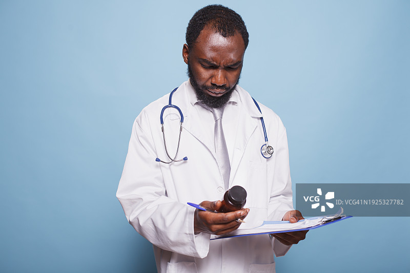 医生在蓝色背景下手拿剪贴板的肖像图片素材
