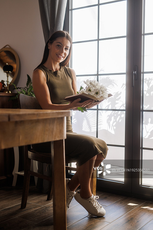 手持一本内有雏菊花的打开的书图片素材