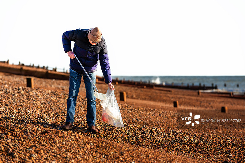 清理海滩塑料垃圾的年长男人图片素材