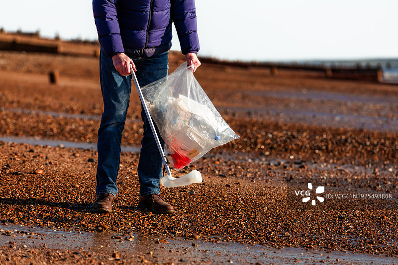 清理海滩塑料垃圾的年长男人图片素材