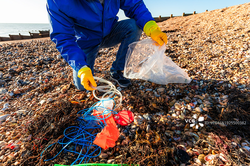 中年男子清理海滩上的塑料垃圾图片素材