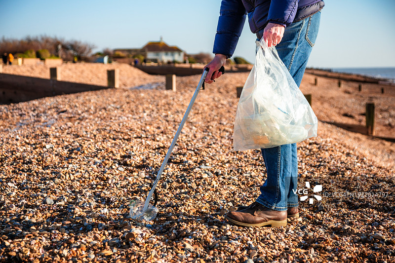 清理海滩塑料垃圾的年长男人图片素材