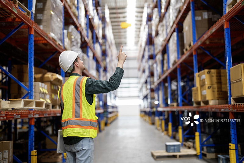 男人工人在仓库货架上清点纸箱产品图片素材