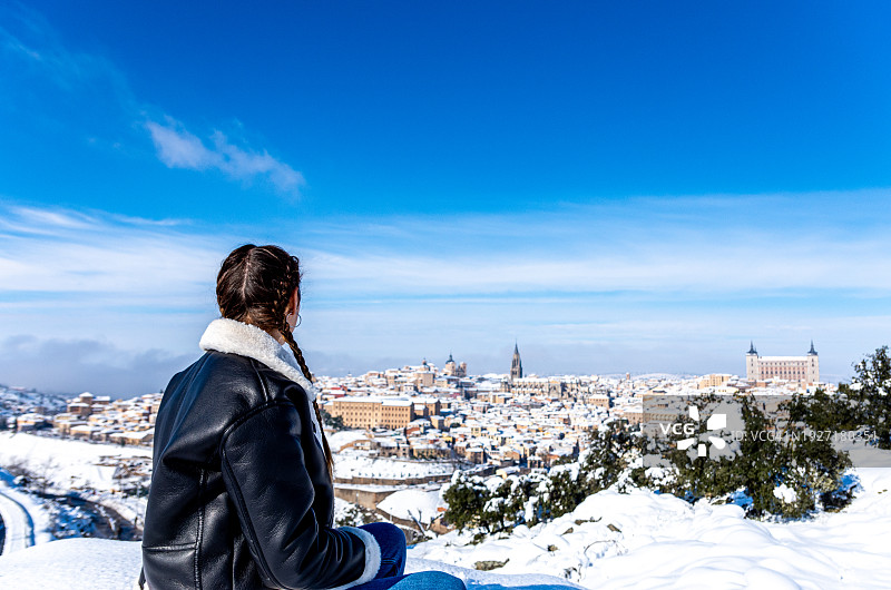 编着辫子，从瞭望点观察白雪覆盖的托莱多市的白人女性图片素材