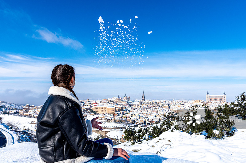编着辫子，从瞭望点观察白雪覆盖的托莱多市的白人女性图片素材