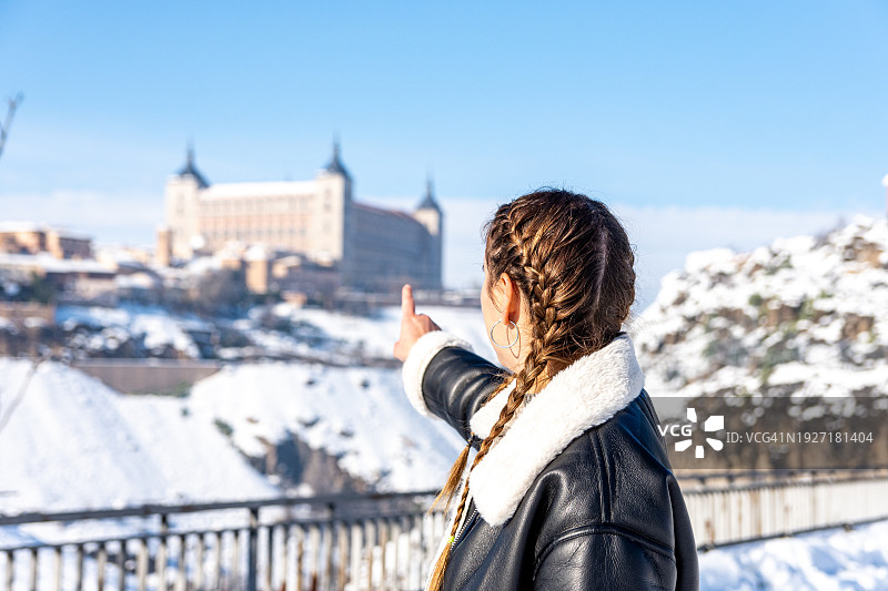 女人指向托莱多城堡，雪景图片素材