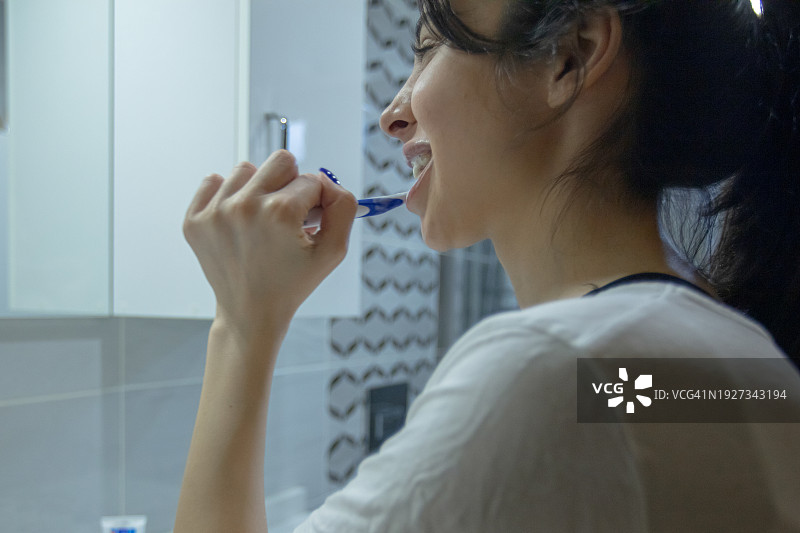 年轻的黑发女子正在刷牙。图片素材
