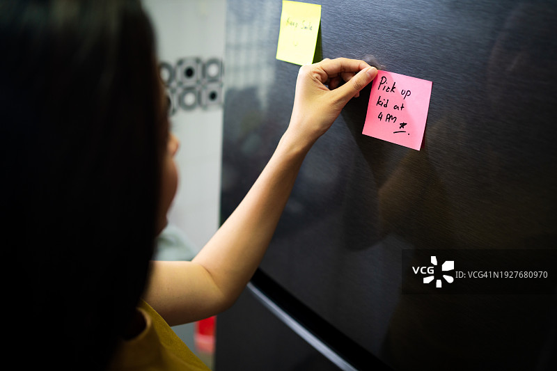 女人将空白待办事项清单贴在厨房冰箱门上图片素材