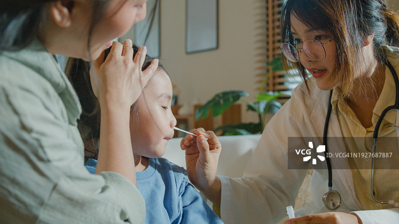 生病发高烧的亚洲女孩在家接受医生鼻拭子检测图片素材
