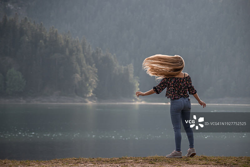 站在湖边欣赏美丽自然风光的年轻女人图片素材