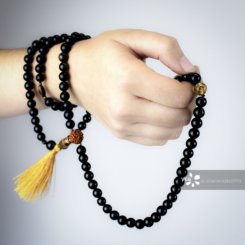 女子手持项链的局部特写，白色背景图片素材