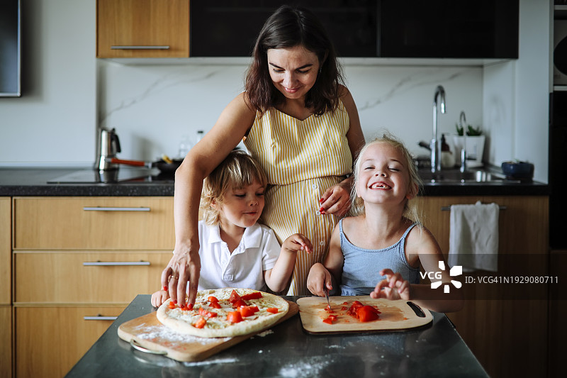 家庭和谐：中年孕妇和两个孩子在家一起做披萨，享受家庭时光，妈妈管理家务图片素材