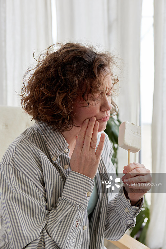 女人在家拿着香草冰棒，难受地眯着眼睛图片素材