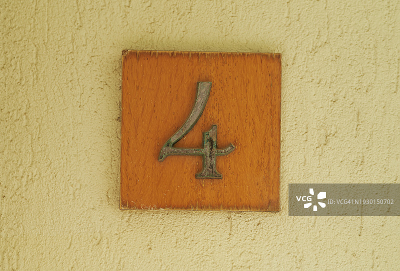 墙上刻有数字“4”的金属牌匾正面特写图片素材