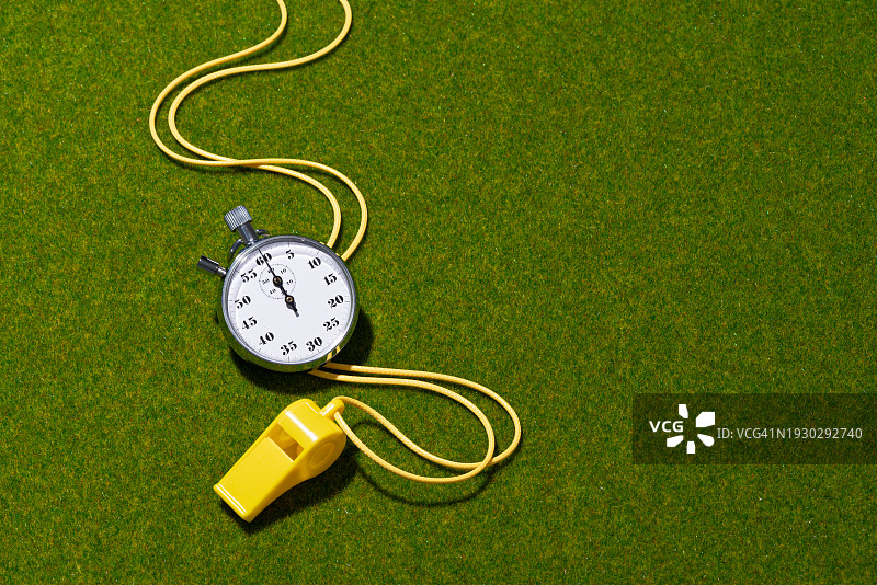 绿色草地上的黄色哨子和秒表图片素材