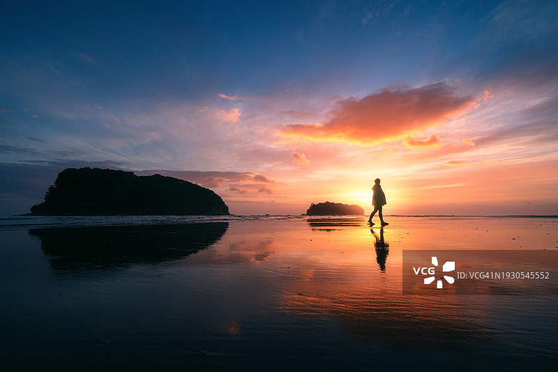 日出时分，走在新西兰海滩上的女人，日落倒影，风景摄影图片素材