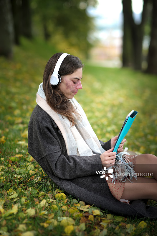 户外自由职业：中年妇女在公园管理任务，使用平板电脑和耳机工作图片素材
