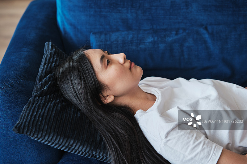 人物与情绪：躺在沙发上的沮丧的亚洲年轻女人，倦怠和情绪耗竭图片素材