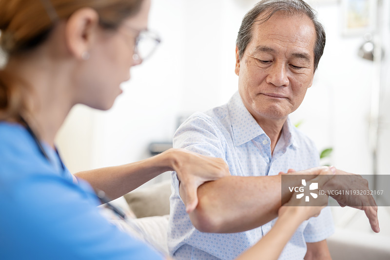 按摩疗法加速老年人伤病康复。居家护士帮助一位亚洲老人按摩手部，并通过物理疗法缓解重症肌无力。图片素材