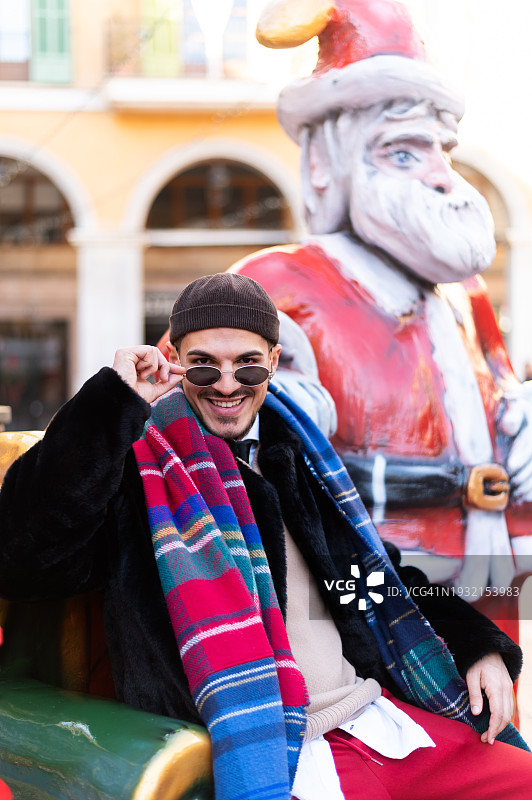坐在圣诞老人雕像旁边的酷炫男人图片素材