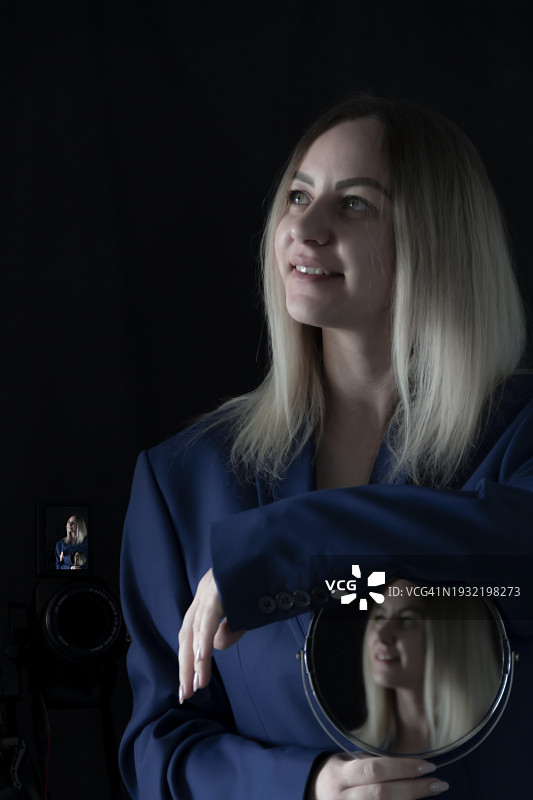 蓝色外套金发美丽女孩的镜中倒影肖像图片素材