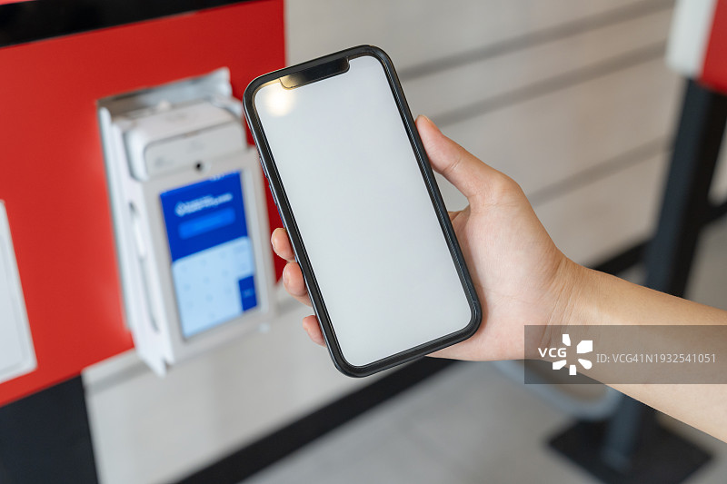 年轻女性在自助点餐机上使用手机进行非接触式支付图片素材