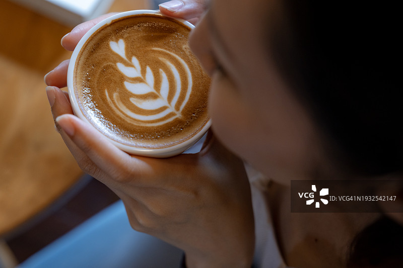 坐在咖啡店享受阳光温暖并喝热咖啡的女人俯视图图片素材