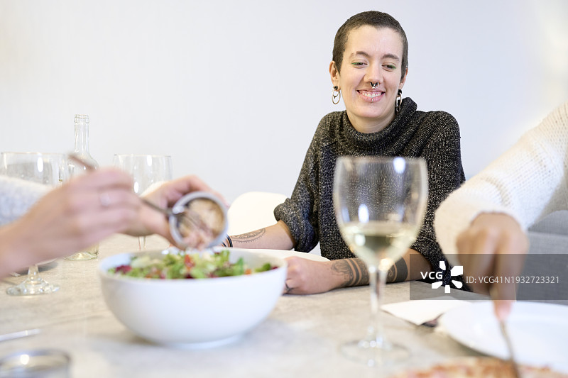 朋友聚餐，女子在沙拉上放罐头肉图片素材