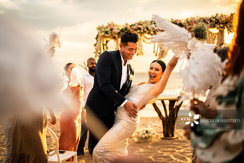 新婚夫妇在海滩婚礼上与宾客庆祝图片素材