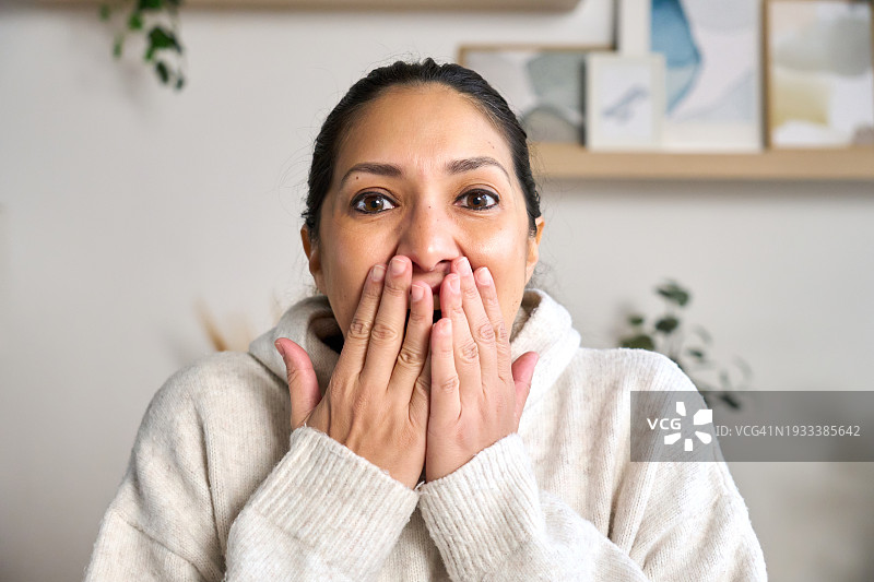 坐在沙发上，收到好消息后捂住嘴巴的女人图片素材
