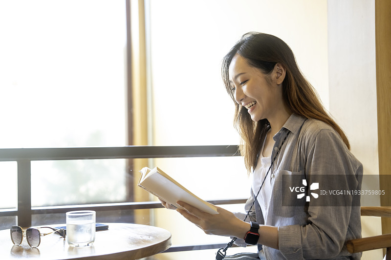 在咖啡馆里读喜爱书籍的女人图片素材