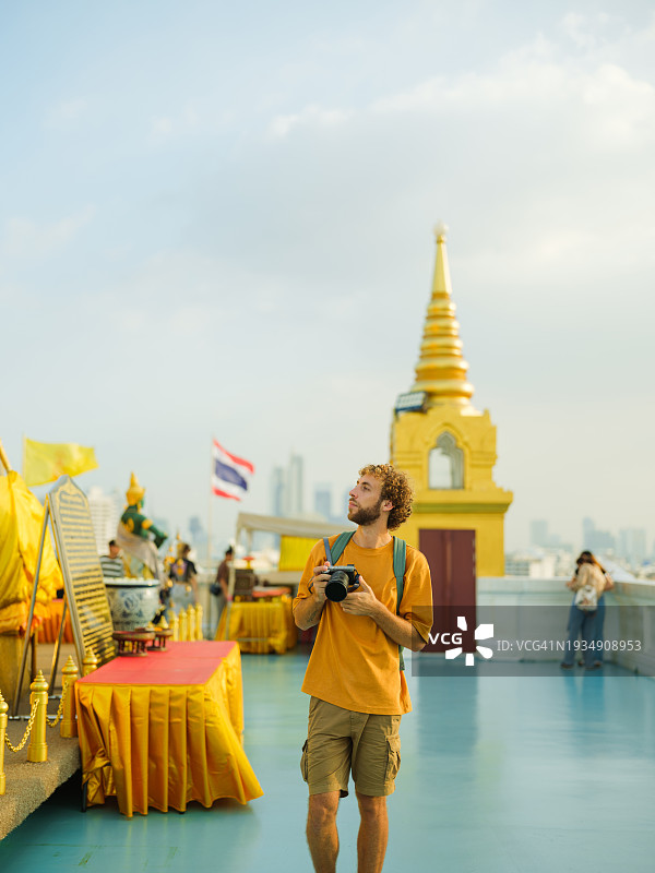 男子在曼谷金色佛塔前用相机拍照图片素材