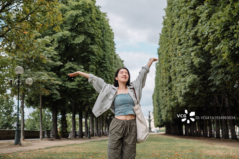 阳光明媚的日子里，年轻的亚洲女性在公园草地上呼吸新鲜空气图片素材