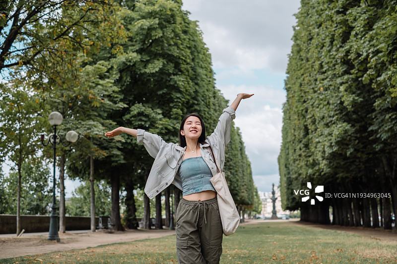 阳光明媚的日子里，年轻的亚洲女性在公园草地上呼吸新鲜空气图片素材