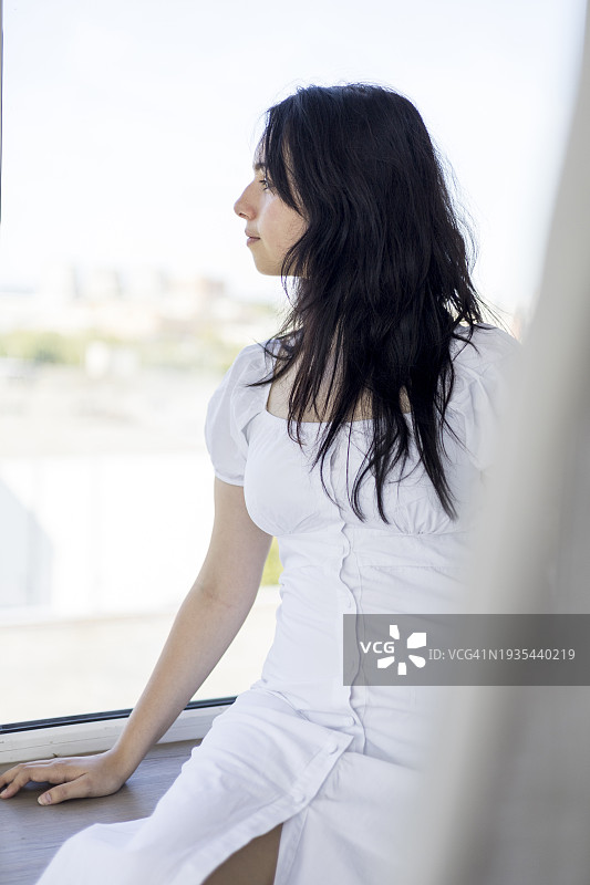 坐在窗台上看城市的年轻漂亮女孩图片素材