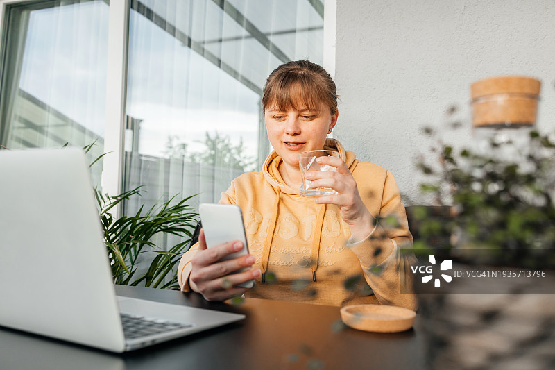 坐在沙发上用手机和笔记本电脑工作的胖女孩图片素材