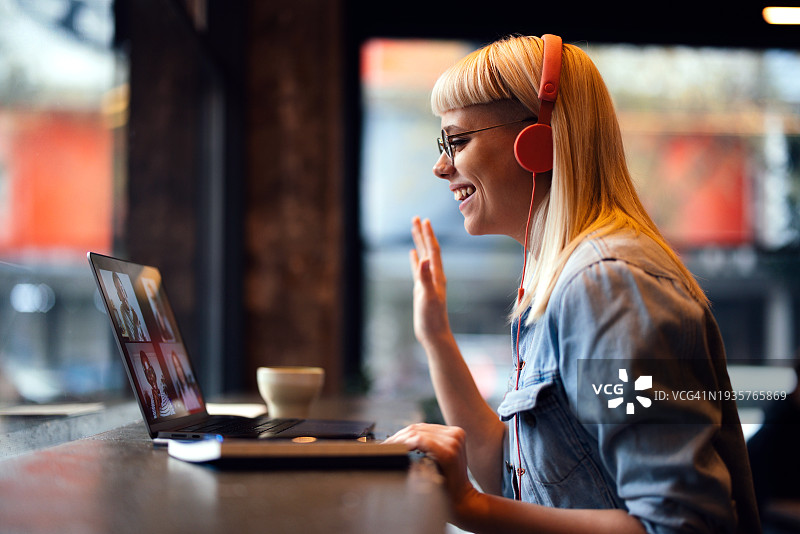 在咖啡馆用笔记本电脑进行在线会议的快乐年轻女子肖像（留白）图片素材